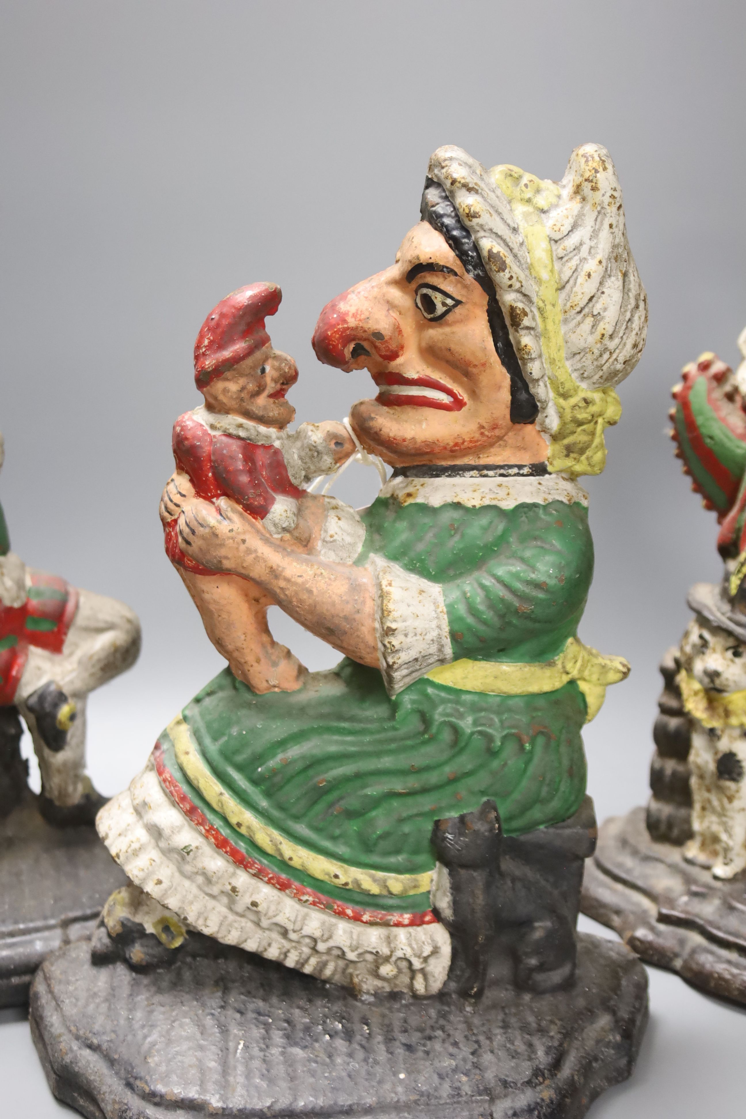 A pair of Victorian cast iron Punch and Judy door stops (later painted), one other and a pair of painted figural cast metal candlesticks, tallest 33cm